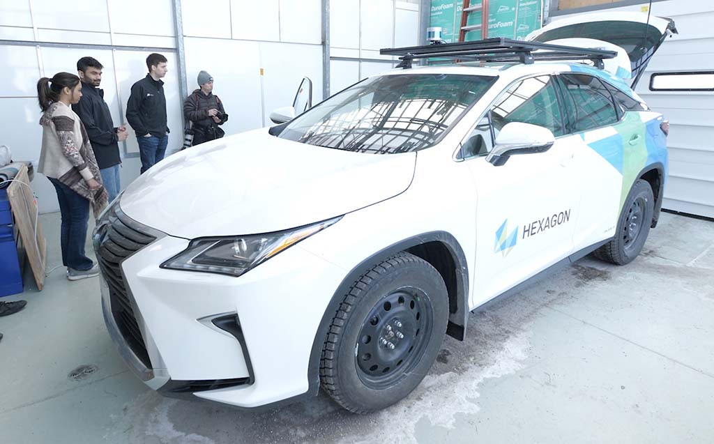 People standing next to autonomous vehicle in a garage